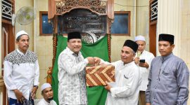 Bupati Bireuen, H Mukhlis menyerahkan bantuan kepada Imuem Syik Mesjid Nurul Huda Blang Guron, Tgk M Yunus