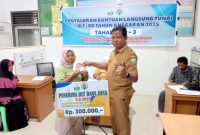 Keuchik Pulo Ara Geudong Teungoeh, Azhar menyerahkan BLT kepada salah seorang penerima, Selasa (29/4)