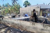 Tim pemadam kebakaran Pos Simpang Mamplam, menyiram puing-puing rumah Afifuddin yang ludes terbakar tadi siang.