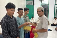 Pj Keuchik Geulanggang Baro, Ir Zairipan ST menyerahkan santunan kepada anak-anak yatim di meunasah, Senin (16/3) malam