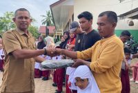 Kepala SDN 19 Juli, Ismadi S.Pd menyerahkan hadiah tas kepada siswa baru sekolah itu, Senin (13/7)