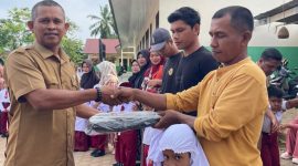 Kepala SDN 19 Juli, Ismadi S.Pd menyerahkan hadiah tas kepada siswa baru sekolah itu, Senin (13/7)