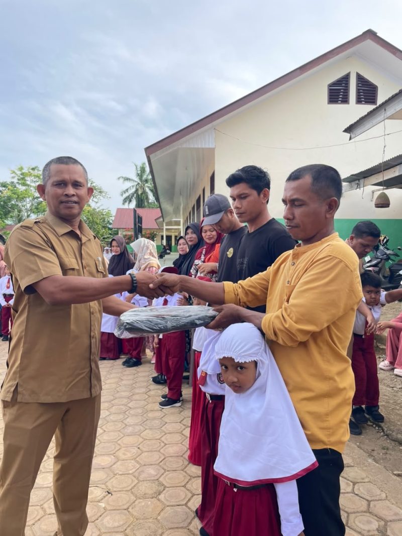 Kepala SDN 19 Juli, Ismadi S.Pd menyerahkan hadiah tas kepada siswa baru sekolah itu, Senin (13/7)