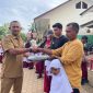Kepala SDN 19 Juli, Ismadi S.Pd menyerahkan hadiah tas kepada siswa baru sekolah itu, Senin (13/7)