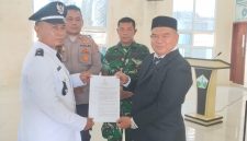 Camat Kota Juang, Saifuddin S.KM M.Kes menyerahkan SK kepada Keuchik Geulanggang Baro, Syafruddin usai prosesi pelantikan di aula Kantor Camat, Sabtu (15/08)
