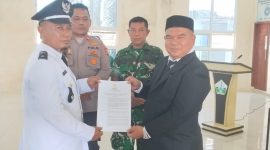 Camat Kota Juang, Saifuddin S.KM M.Kes menyerahkan SK kepada Keuchik Geulanggang Baro, Syafruddin usai prosesi pelantikan di aula Kantor Camat, Sabtu (15/08)