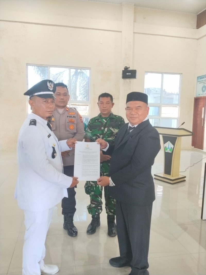 Camat Kota Juang, Saifuddin S.KM M.Kes menyerahkan SK kepada Keuchik Geulanggang Baro, Syafruddin usai prosesi pelantikan di aula Kantor Camat, Sabtu (15/08)